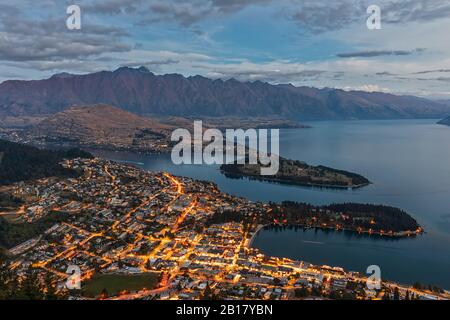 Nuova Zelanda, Otago, Queenstown, città sulla riva del lago Wakatipu al crepuscolo con montagne sullo sfondo Foto Stock