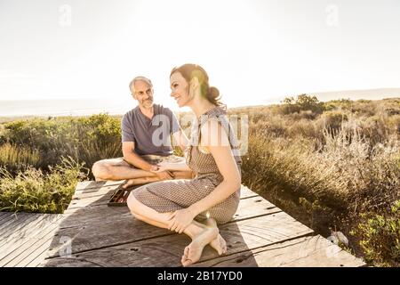 Coppia seduta sul lungomare in costa giocando backgammon Foto Stock