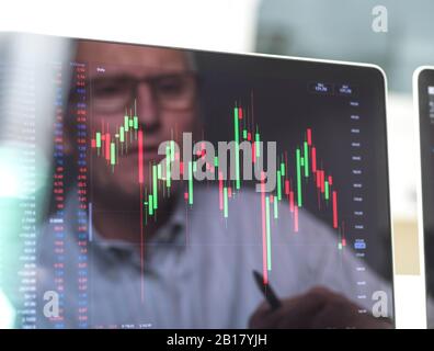 Riflessione di un operatore di borsa che visualizza sullo schermo le prestazioni di un prezzo di azione dell'azienda Foto Stock