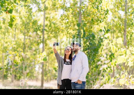 Coppia sorridente che prende un selfie in un parco Foto Stock