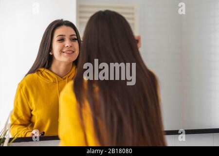 Immagine speculare della ragazza adolescente applicazione di mascara Foto Stock