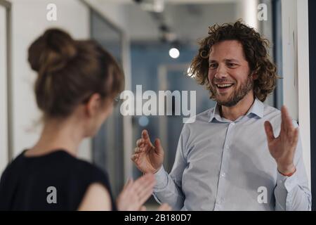 Imprenditore sorridente e imprenditrice parlando in ufficio Foto Stock