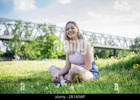 Ritratto di felice giovane donna rilassante su un prato in estate, Berlino, Germania Foto Stock