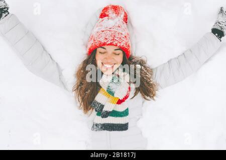 Ritratto di donna felice sdraiata sulla neve Foto Stock