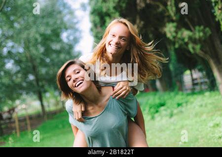 Ritratto di giovane donna felice che porta un amico piggyback Foto Stock