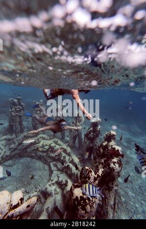 Donna un uomo che nuota vicino a sculture subacquee fatte da Jason deCaires Taylor, isola di Gili Meno, Bali, Indonesia Foto Stock