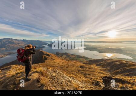 Donna che scatta una foto al Roys Peak, Wanaka City e al Lago Wanaka, Nuova Zelanda Foto Stock