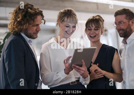 Buon team aziendale che ha una riunione in ufficio con un tablet Foto Stock