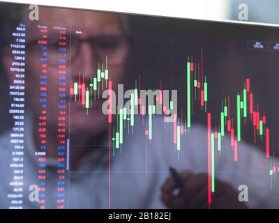 Riflessione di un operatore di borsa che visualizza sullo schermo le prestazioni di un prezzo di azione dell'azienda Foto Stock