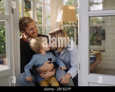 Famiglia felice e affettuosa in sala da sole a casa Foto Stock