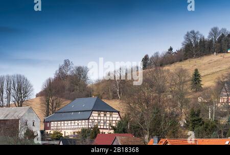 Hinterhermsdorf, Germania. 20th Feb, 2020. Vicino ad altre case di Hinterhermsdorf si trova una casa Umgebande ristrutturata e restaurata. Le case a graticcio dell'Alto Lusaziano, costruite principalmente a metà del 19th secolo, caratterizzano ancora l'architettura del villaggio nell'alta Lusazia, un'area nel sud-est della repubblica vicino al confine con la Repubblica Ceca. Merito: Matthias Rietschel/dpa-Zentralbild/ZB/dpa/Alamy Live News Foto Stock