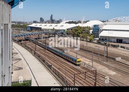 Un treno singolo corre lungo una delle tante linee che si alimentano nel centro di Melbourne tra la MCG (a sinistra) e lo stadio di calcio AAMI Foto Stock