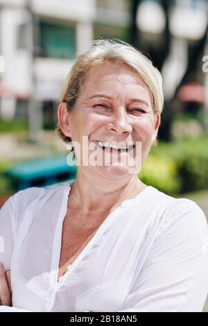 Ritratto di donna sorridente in blusa di cotone bianco che trascorre una giornata di sole all'aperto Foto Stock