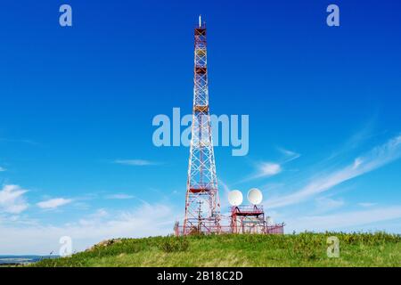 Torre della televisione digitale su una collina contro il cielo blu. Ripetitore. Foto Stock