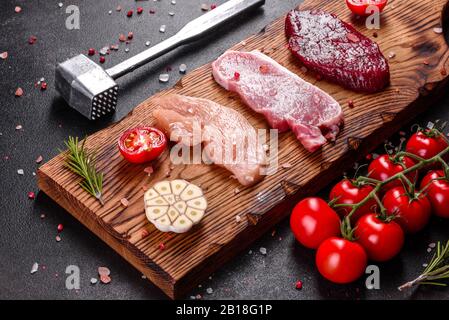 Bistecca fresca succosa di manzo, maiale e pollo con verdure pronte per cucinare. Bistecche di diverse varietà di carne preparate per cucinare Foto Stock