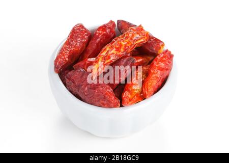 Pepe di Cayenne essiccato in una ciotola bianca su sfondo bianco. Chiamato anche spezia di Guinea, pepe di corno di mucca, aleva, pepe di uccello, pepe rosso, peperoncino piccante Foto Stock