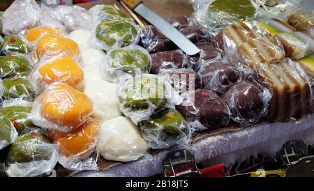 In vendita una varietà di torte e dolci al riso al vapore, confezionati singolarmente in involucri di plastica. Foto Stock