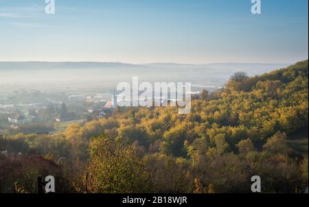 Bella immagine di paesaggio di un villaggio in una valle, circondato da alberi con foglia di autunno colore Foto Stock