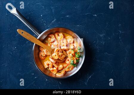 Piatto americano per la giornata nazionale dello scampi - cotto con salsa di burro all'aglio servito con limone e prezzemolo, su una padella su fondo di cemento, Foto Stock