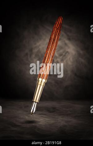 Penna stilografica di lusso con struttura in legno su sfondo marrone astratto. Foto Stock