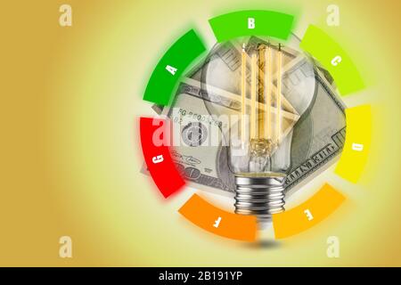 Concetto di efficienza energetica delle lampade a LED. Diminuzione del consumo di energia elettrica. Lampadina a LED con dollari su sfondo giallo. Tavola circolare. Foto Stock