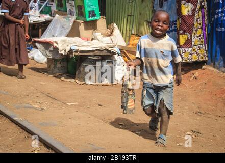 Kibera, Nairobi, Kenya - 13 febbraio 2015: Un povero ragazzo nero delle baraccopoli di Kibera che gioca con i rifiuti Foto Stock