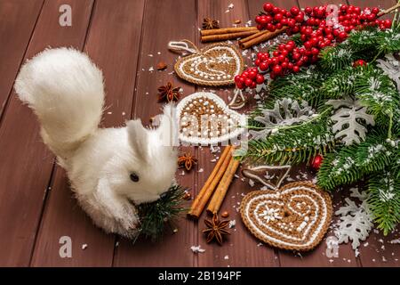 Sfondo di Natale. Capodanno abete, rosa canina, foglie fresche, uncinetto zenzero biscotti cuori, spezie e neve artificiale. Tavole di legno sfondo Foto Stock