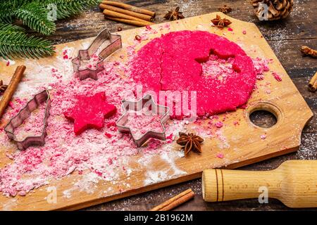 Biscotti allo zenzero rosso da cucina. Dolci di Natale tradizionali. Festive sfondo culinario. Abete, spezie, tagliabulloni, pasta cruda, spilla, vù Foto Stock
