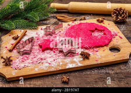 Biscotti allo zenzero rosso da cucina. Dolci di Natale tradizionali. Festive sfondo culinario. Abete, spezie, tagliabulloni, pasta cruda, spilla, vù Foto Stock