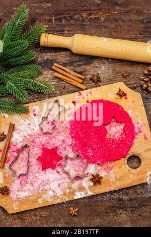 Biscotti allo zenzero rosso da cucina. Dolci di Natale tradizionali. Festive sfondo culinario. Abete, spezie, tagliabulloni, pasta cruda, spilla, vù Foto Stock