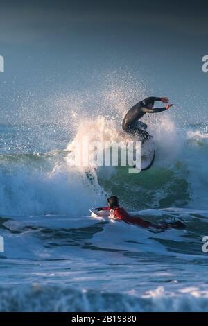 Spettacolare surf azione come un surfista cavalcare la cresta di un onda a Fistral a Newquay in Cornovaglia. Foto Stock