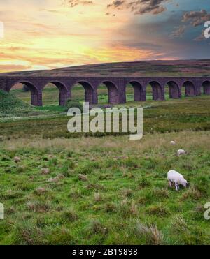 Tramonto sul Viadotto Ribblehead che porta la linea ferroviaria Settle-Carlisle attraverso la Ribble Valley a Ribblehead, North Yorkshire, Inghilterra Foto Stock