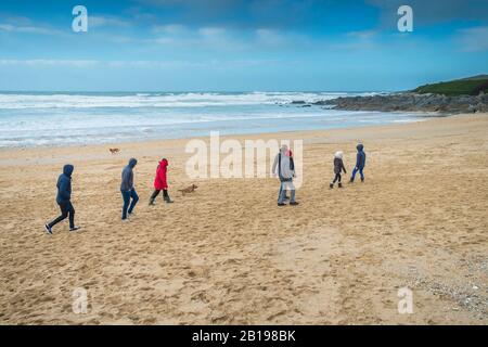 Le persone che si godono una passeggiata a rischio nel clima fresco e ventoso sulla spiaggia di Fistral a Newquay in Cornovaglia. Foto Stock