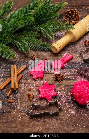Biscotti allo zenzero rosso da cucina. Dolci di Natale tradizionali. Festive sfondo culinario. Abete, spezie, tagliabulloni, pasta cruda, spilla, vù Foto Stock
