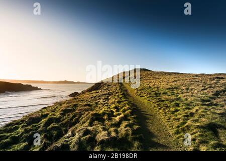 Un sentiero che conduce ad una barraga dell'età del bronzo sulla cima dell'Isola di Porth, Trevelgue Head a Newquay in Cornovaglia. Foto Stock