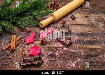 Biscotti allo zenzero rosso da cucina. Dolci di Natale tradizionali. Festive sfondo culinario. Abete, spezie, tagliabulloni, pasta cruda, spilla, vù Foto Stock