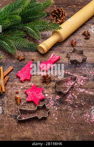 Biscotti allo zenzero rosso da cucina. Dolci di Natale tradizionali. Festive sfondo culinario. Abete, spezie, tagliabulloni, pasta cruda, spilla, vù Foto Stock