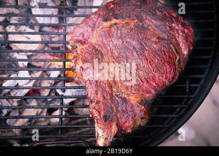 Un succoso pezzo grigliato di bistecca di Tomahawk su una griglia barbecue a carbone sormontato da sale Himalyan Foto Stock