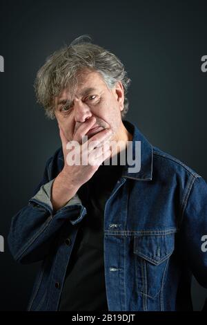 Ritratto di un uomo con giacca in denim blu su sfondo sfumato Foto Stock