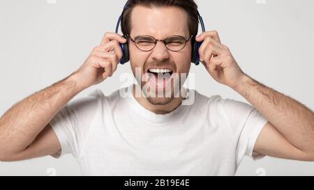 Head shot studio ritratto overjoyed giovane ragazzo indossando cuffie wireless. Foto Stock