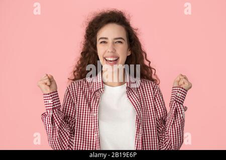 Felicemente felice donna millenaria che stringe i pugni, celebrando le notizie di vincita. Foto Stock