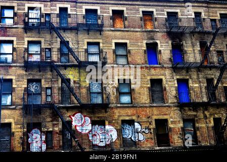 Vecchio blocco di appartamenti a Mid Town Manhattan, New York City, USA, caratterizzato da una fuga esterna di fuoco con pareti graffite. Foto Stock