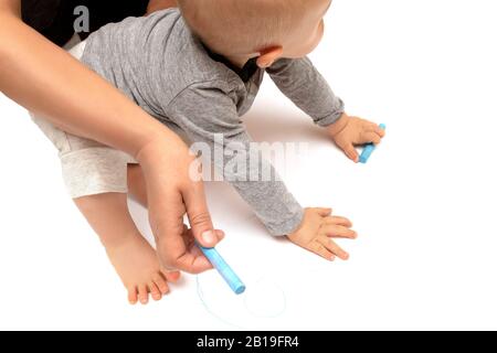Le mani del bambino sono dipinte con pastelli colorati su un foglio bianco di carta Foto Stock