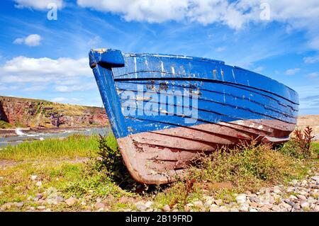 Un'antica barca di legno lasciata spianata sul litorale ad Auchmithie, da Arbroath. Foto Stock