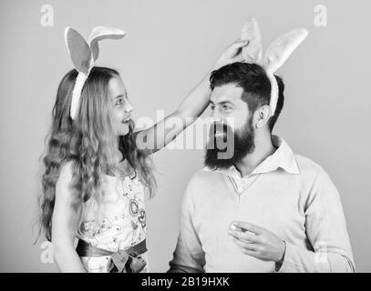 Ultimi preparativi. Famiglia alla caccia annuale di uova di Pasqua. Buona famiglia. Famiglia che celebra la Pasqua. Padre e bambino con uova di Pasqua colorate. Famiglia di padre e figlia che sorride in orecchie di coniglietto di Pasqua. Foto Stock