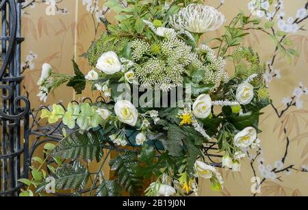 Decorazione artificiale in plastica con fiori bianchi e foglie verdi. Foto Stock