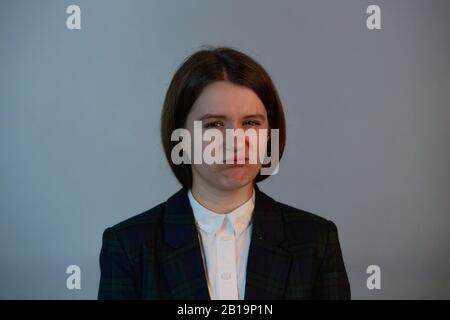 Infastidita giovane donna che guarda serio alla fotocamera isolato su sfondo grigio. Donna di affari che ha uno sguardo arrabbiato e che guarda alla macchina fotografica. Foto Stock