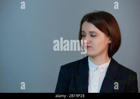 Infastidita giovane donna e rotolando gli occhi dal fastidio, ascoltando sciocchezze o noioso conversazione, in piedi sul muro grigio. Foto Stock