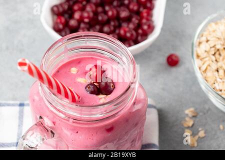 Frullato appena fatto in casa con mirtilli rossi, farinata d'avena e yogurt in un vaso tazza su un tavolo grigio. Concetto di alimentazione sana, primo piano. Foto Stock