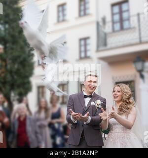 primo piano. sposa felice e sposo che libera colombe bianche Foto Stock